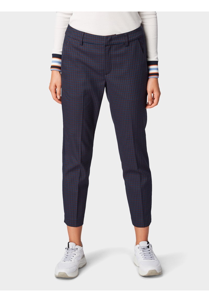 Granatowe spodnie w kratkę o wąskim kroju, charakteryzujące się gładką fakturą, subtelnym wzorem kraty, kieszeniami z przodu i dopasowanymi kostkami. Połączone z białymi sneakersami.