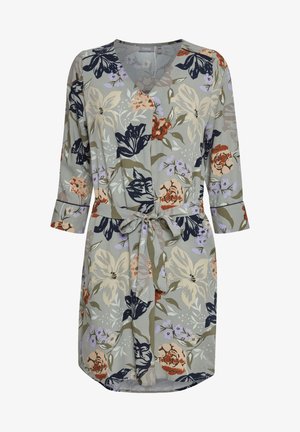 Žalia gėlėta suknelė su V formos iškirpte, ilgomis rankovėmis ir rišamu juosmeniu. Puikiai išryškinti dideli, daugiaspalviai gėlės ir lapai.