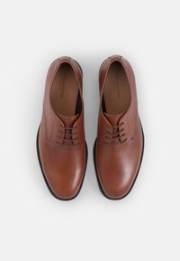 Chaussures habillées en cuir marron avec une texture lisse, design classique à lacets et bout rond. Couture discrète le long des bords.