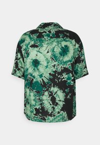 Chemise à manches courtes avec motifs spirales tie-dye verts et noirs, montrée de dos sur fond blanc uni.