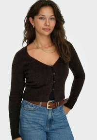 Dark brown fuzzy cardigan with a V-neckline, long sleeves, and five buttons. Paired with high-waisted blue jeans and a brown belt.