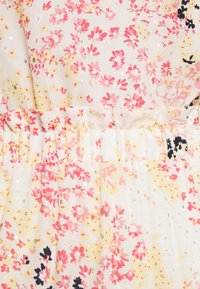 Tissu floral avec des fleurs roses, jaunes et noires sur un fond clair. Taille froncée et accents dorés éparpillés. Texture douce et légère.