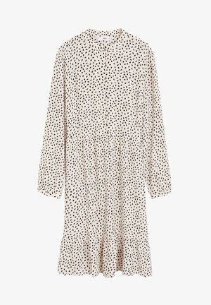 Vestido de manga larga color crema con patrón de puntos irregulares en negro, con botones en el frente, cuello y dobladillo con volantes.