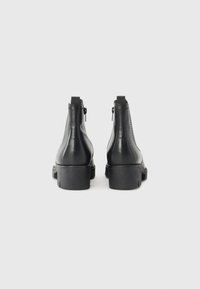 Schwarze Leder Stiefeletten mit glatter Oberfläche, ausgestattet mit einem Blockabsatz, seitlichem Reißverschluss und dezenten Nähdetails.