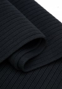 Donker geribd stoffen materiaal met een zachte textuur, voorzien van een opgerolde rand. De kleur is effen zwart, met duidelijke verticale ribbels.