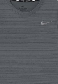 Grå Dri-FIT tanktop med et tekstureret stribet mønster, rund halsudskæring og et reflekterende sølvfarvet Nike-logo på brystet.