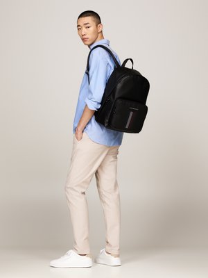 Zaino nero con una texture liscia, forma rettangolare, tasca frontale con zip e un motivo decorativo a strisce rosse e blu.