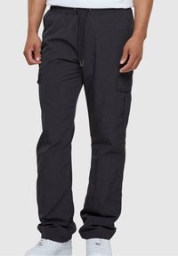 Kapsáčové kalhoty z tmavě šedé látky, s elastickým pasem, nastavitelným stahovacím šňůrkou a bočními kapsami. Texturovaný povrch s volným střihem.
