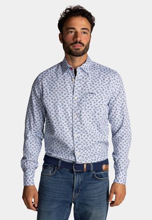Lichtblauw overhemd met knopen, voorzien van een bloemenpatroon, lange mouwen en een zak. Gecombineerd met donkerblauwe jeans en een gevlochten riem.