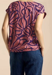 Short-sleeve top in soft, lightweight fabric featuring a pink base with dark purple floral patterns, gathered hem, and casual fit.