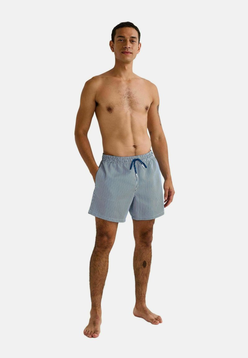 Shorts de bain rayés bleus et blancs avec une taille élastique et un cordon de serrage. Le tissu semble léger et respirant.