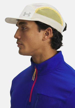 White cap with mesh side panel, yellow accents, and grey logo. Blue zip-up jacket with a patch pocket and contrasting red zipper detail.