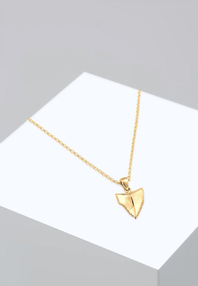 Collana d'oro con un pendente a forma di dente di squalo con bordi seghettati, attaccato a una delicata catena. Design semplice e moderno.