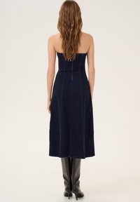 Strapless, navy denim dress with a fitted bodice and A-line skirt, featuring vertical seams and a mid-calf length. Smooth texture.