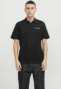 Sort bomuld polo shirt med krave og korte ærmer, med et hvidt "JACK & JONES" logo på venstre bryst og en lige bund.