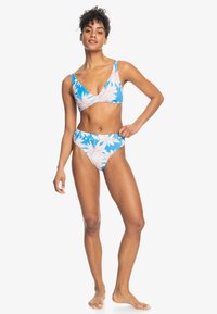 Bikini-set med en blå bakgrund och mönster av rosa och vita löv. Toppen har en V-ringning, och byxorna är högmidjade.