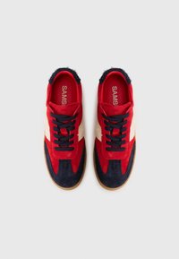 Røde og marineblå ruskindsneakers med en crème-stribe, tekstureret stof, rund tå, flad snørefunktion og gummisål. Mærkenavnet er synligt indvendig.