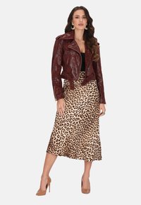Burgundowa skórzana kurtka motocyklowa o dopasowanym kroju, zestawiona z satynową spódnicą midi w gepardzi wzór. Modelka ma na sobie beżowe szpilki.