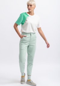 Groen en wit color-block t-shirt met decoratieve details, gecombineerd met mintgroene joggingbroek. Heeft elastische boorden en subtiele stiksels.