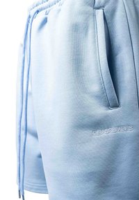 Shorts en coton bleu clair avec une ceinture élastique, des poches latérales, des cordons de serrage et "ELIASRUMELIS" brodé près de la poche.