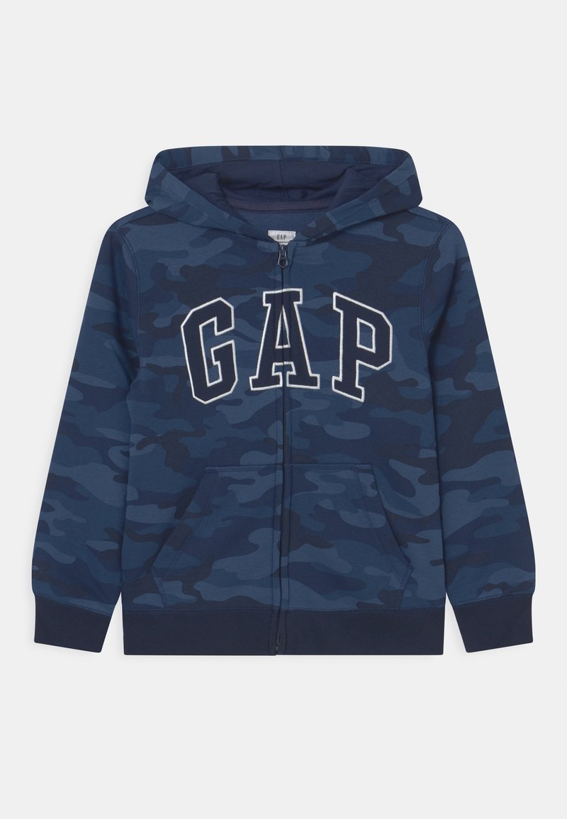 Sweat à capuche zippé bleu marine avec motif camouflage, arborant le logo "GAP" en blanc, poches kangourou, et poignets et ourlet côtelés.