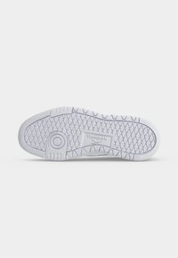 Hvid Reebok sneakersål med tekstureret grebsmønster og cirkulært drejepunkt, vist på en ensartet lys baggrund.