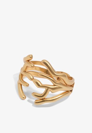 Złoty pierścionek o otwartym wzorze przypominającym abstrakcyjne gałęzie koralowca, polerowane wykończenie, rzucający miękkie cienie na białym tle.