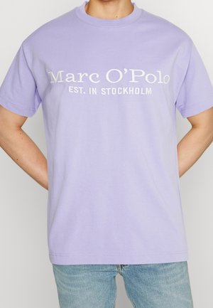 T-shirt en coton lilas avec un col rond et des manches courtes, comportant un texte brodé blanc indiquant "Marc O'Polo EST. À STOCKHOLM."