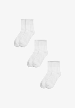 Tres pares de calcetines blancos lisos hasta el tobillo, dispuestos en diagonal sobre un fondo blanco.