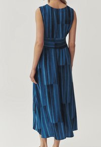 Ärmlös blå maxiklänning med en texturerad tyg med vertikala ränder, rynkad midjedetalj och en svävande A-linjeform.