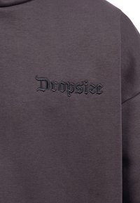 Ciemnoszara bluza, wykonana z mieszanki bawełny, z czarnym haftowanym napisem "Dropsize". Prosty design, teksturowany materiał, styl z okrągłym dekoltem.