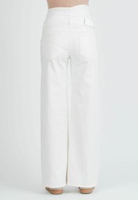 Valkoiset leveälahkeiset farkut, joissa on korkea vyötärö, sisältäen kaksi takataskua ja sileän, teksturoidun pinnan. Helma on suora ja lattiaan asti ulottuva.