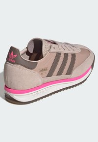 Béžová teniska z broušené kůže a látky se třemi hnědými pruhy, růžovými akcenty, texturovaným límcem a bílou podrážkou s gumovým vzorkem.