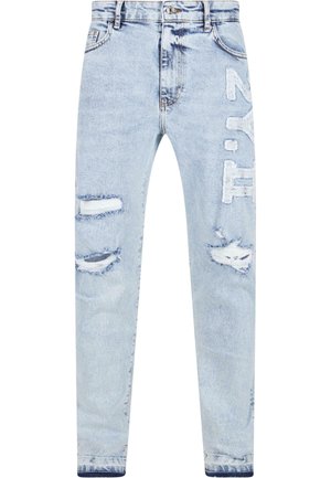 Jeans de mezclilla azul claro con detalles desgastados, incluyendo desgarros y parches. Tela texturizada con diseño de pierna recta y cierre de botón.