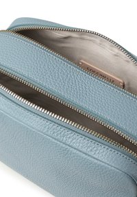 Borsetta in pelle azzurro chiaro con due scomparti con cerniera, dotata di dettagli in metallo color oro e una finitura morbida e testurizzata. Interno foderato in tessuto beige.