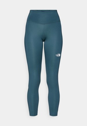Teal high-waisted leggings made of stretchy fabric. Features a small white logo on the left side and stitched detailing along the seams.