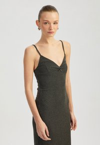 Dunkelgraues, tailliertes Kleid mit dünnen Spaghetti-Trägern, einem V-Ausschnitt und einer dezenten Textur. Verfügt über ein dekoratives Knoten-Detail an der Vorderseite.