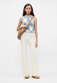 Pleteni brezrokavnik z modrim, belim in sivim argyle vzorcem; v kombinaciji z krema širokimi hlačami in svetlo rjavim čezramenskim nahrbtnikom. Platforme.