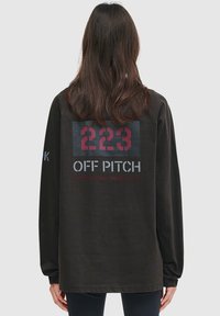Black long-sleeve shirt featuring a large red and grey graphic print with the numbers "223" and the text "OFF PITCH" on the back.