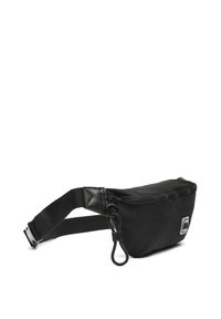 Crni platneni fanny pack s zatvaranjem na patentni zatvarač, podesivim remenom i okruglim logom kao akcentom. Glatka tekstura i kompaktni oblik.