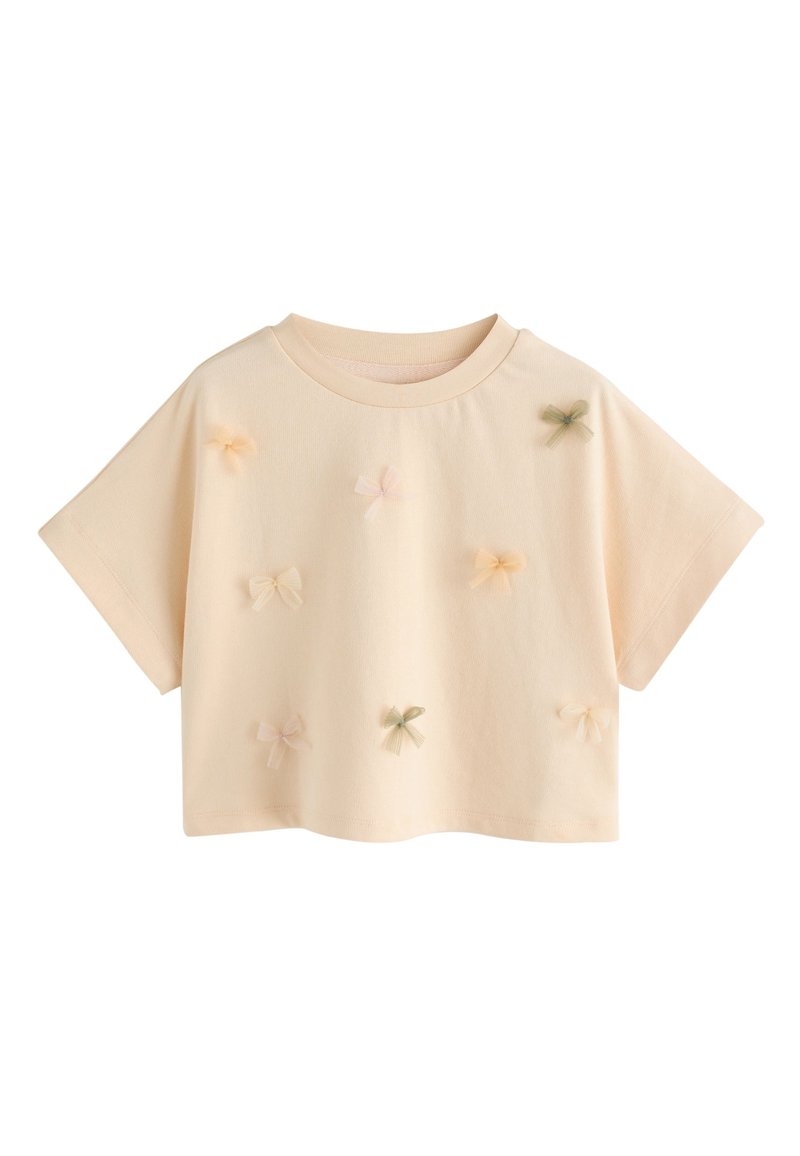 Haut court à manches courtes couleur pêche avec un col arrondi, orné d'appliqués de petits nœuds pastel dispersés en rose, jaune et vert.