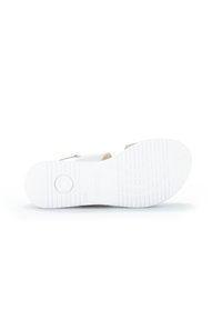 White sandal with a textured rubber sole, adjustable strap, and a smooth upper material. Simple design with minimal accents.