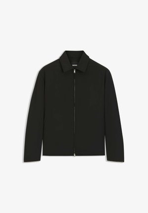 Veste légère noire avec une fermeture éclair intégrale à l'avant et un col classique, présentée sur un fond blanc.