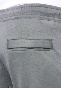 Närupp av grått tyg som visar en bakficka med en horisontell kantstijl och sydd midja på kläder.