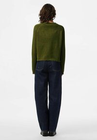 Groene gebreide cropped trui, ronde halslijn, geribbelde zoom, gecombineerd met hoge taille donkerblauwe denim jeans, taps toelopende pasvorm met achterzakken.