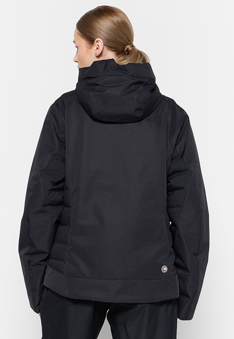 Giacca a vento nera con cappuccio, caratterizzata da un tessuto texturizzato e pannelli lisci a contrasto. Include polsini elastici e un accento con logo.