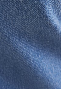 Tessuto di denim blu con una superficie texture, caratterizzato da una leggera lucentezza. La trama è coerente con le tipiche proprietà del denim.