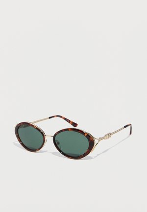 Round tortoiseshell sunglasses with green lenses and thin gold arms featuring decorative knot detail.