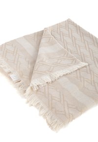 Plaid di coperta intrecciata beige con motivo geometrico, bordi frangiati e una consistenza morbida, piegato ordinatamente.