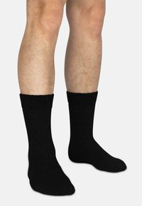 Schwarze Socken aus weichem, strukturiertem Material, mit einem gerippten Bündchen, das knapp über den Knöchel reicht. Klassische Sockeform.